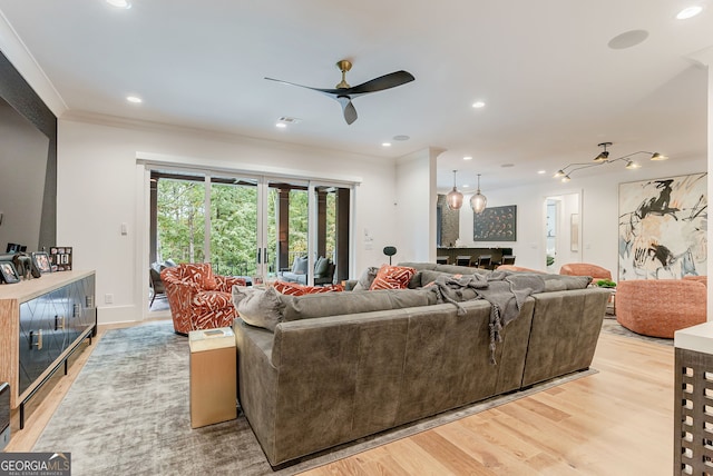 living room with light wood-type flooring, ceiling fan, and crown molding