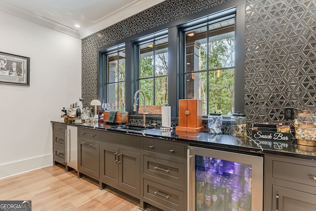 bar with gray cabinets, beverage cooler, light hardwood / wood-style flooring, and crown molding