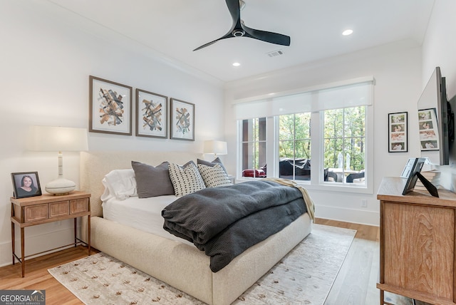 bedroom with light hardwood / wood-style floors, ceiling fan, and crown molding