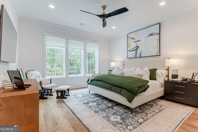 bedroom featuring ceiling fan, light wood-type flooring, and ornamental molding