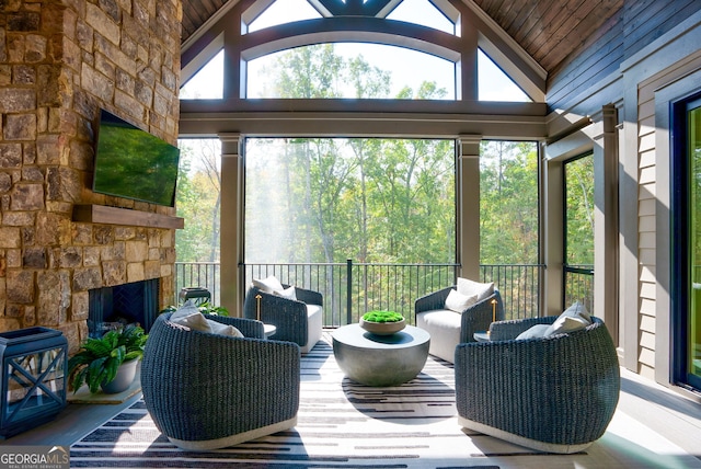 sunroom with vaulted ceiling and an outdoor stone fireplace