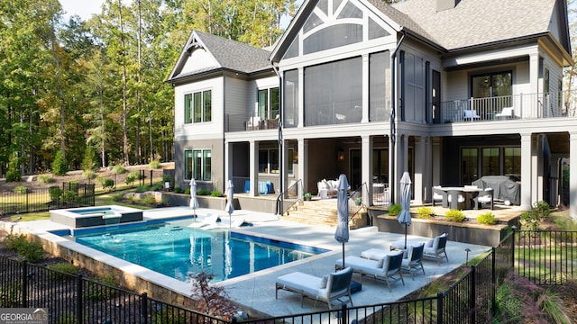 rear view of house featuring a swimming pool with hot tub, an outdoor living space, a patio, and a balcony