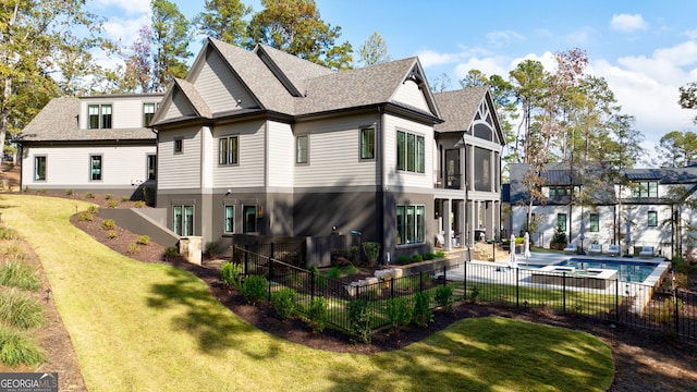 back of house with a fenced in pool, a patio area, a yard, and a sunroom