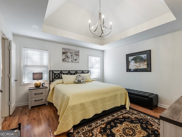 bedroom featuring a tray ceiling, dark hardwood / wood-style flooring, and a notable chandelier