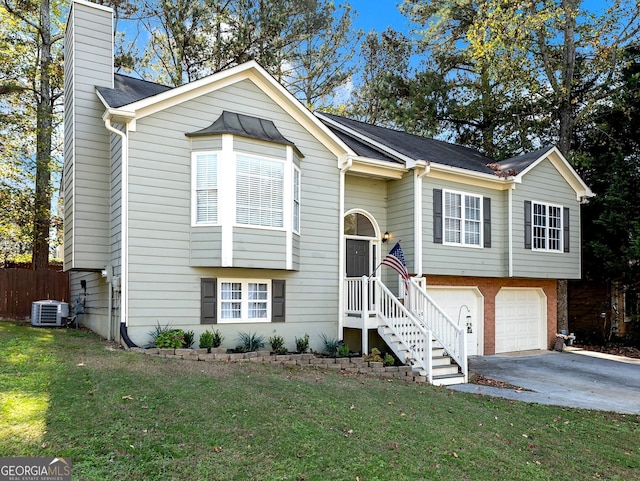 bi-level home with central AC unit, a garage, and a front yard