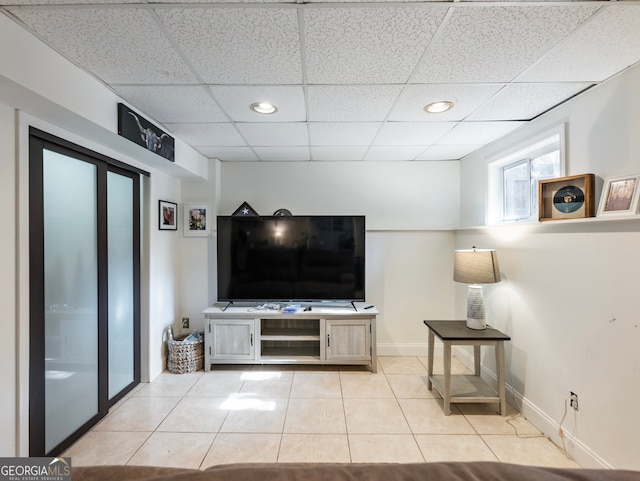 living room featuring a drop ceiling and light tile patterned flooring