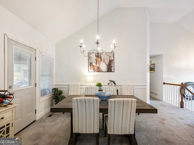 carpeted dining space with a chandelier and vaulted ceiling