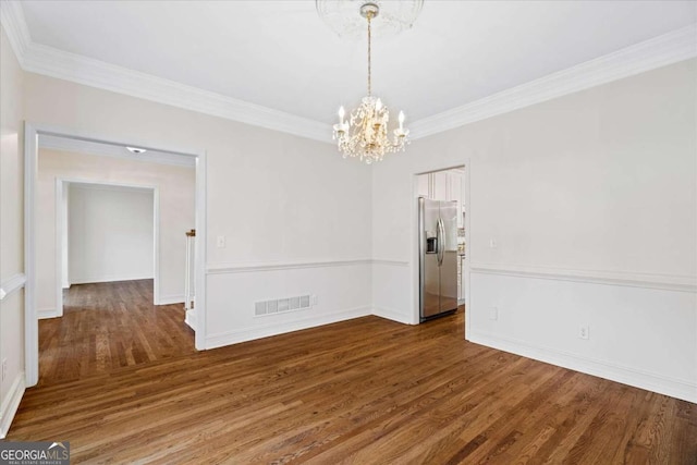 spare room with dark hardwood / wood-style floors, ornamental molding, and an inviting chandelier