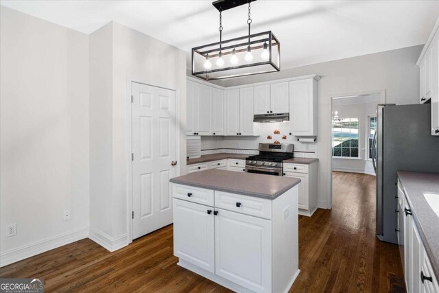 kitchen with appliances with stainless steel finishes, dark hardwood / wood-style flooring, a kitchen island, pendant lighting, and white cabinetry