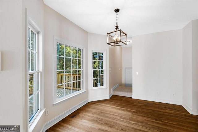 unfurnished dining area featuring hardwood / wood-style flooring and a chandelier