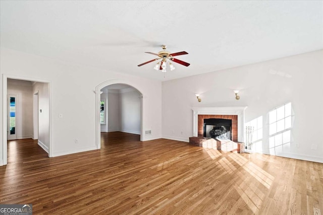 unfurnished living room with ceiling fan, dark hardwood / wood-style flooring, and a brick fireplace