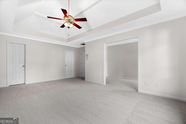 unfurnished room with a tray ceiling, ceiling fan, and light carpet