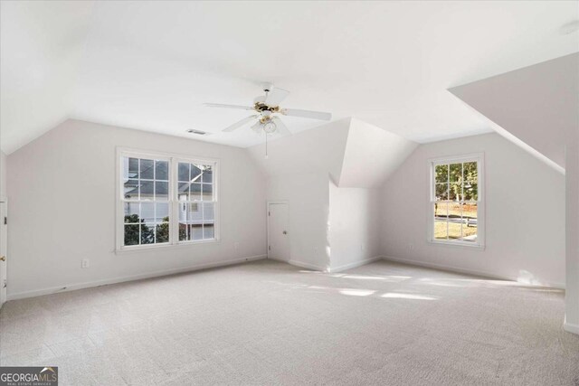 additional living space with ceiling fan, light colored carpet, and vaulted ceiling