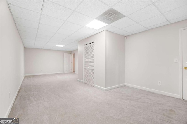 basement featuring light colored carpet and a drop ceiling