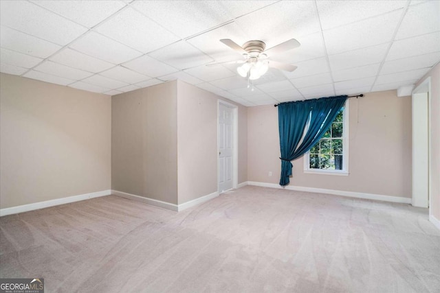 empty room featuring a paneled ceiling, ceiling fan, and light carpet