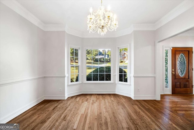 entryway featuring wood-type flooring, ornamental molding, and an inviting chandelier