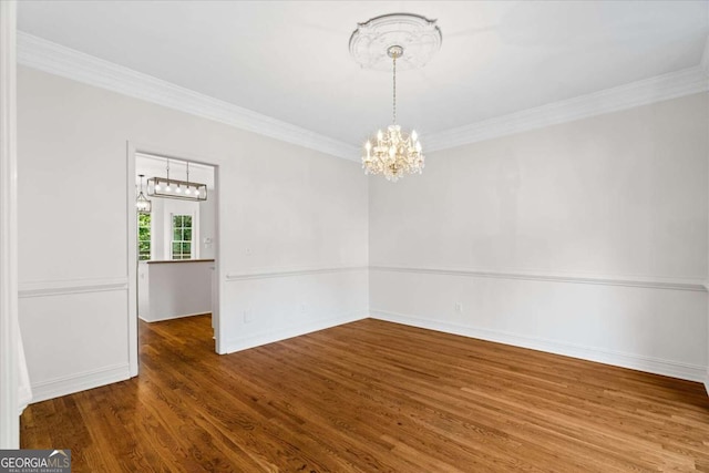 empty room featuring hardwood / wood-style floors, a notable chandelier, and ornamental molding