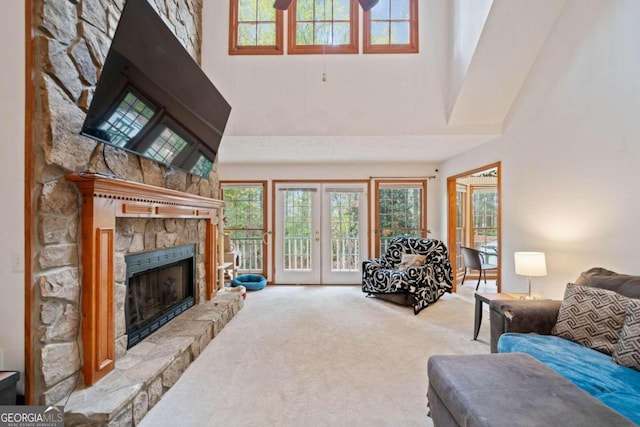 carpeted living room featuring a fireplace, a high ceiling, ceiling fan, and french doors