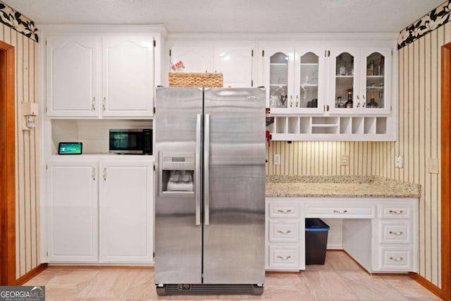 kitchen with white cabinets, appliances with stainless steel finishes, a textured ceiling, and light stone countertops