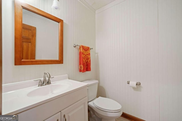 bathroom with wood walls, vanity, toilet, and ornamental molding