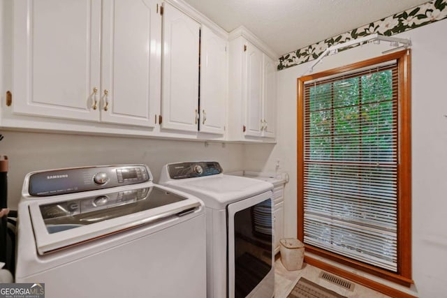 laundry area with cabinets, a textured ceiling, and separate washer and dryer