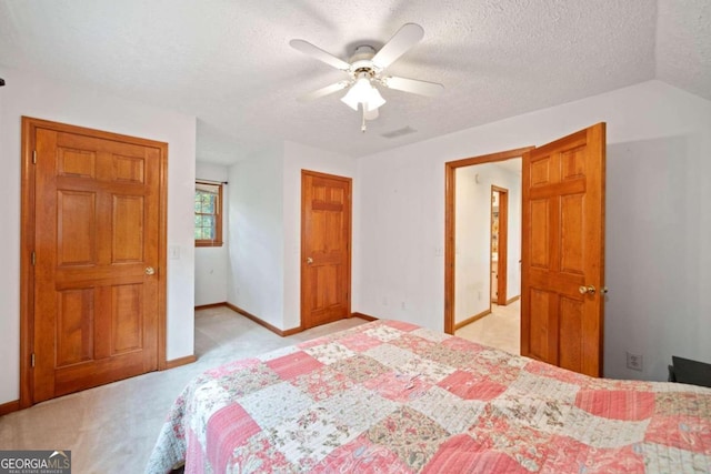 bedroom featuring a textured ceiling, light colored carpet, and ceiling fan