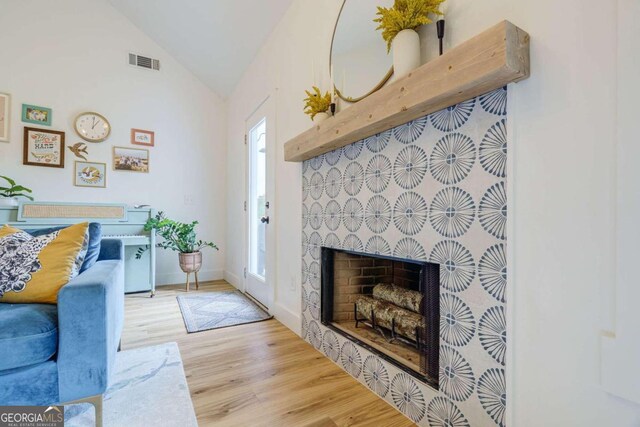 living room featuring a healthy amount of sunlight, light hardwood / wood-style flooring, and vaulted ceiling