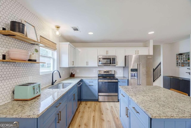 kitchen with tasteful backsplash, appliances with stainless steel finishes, sink, light hardwood / wood-style floors, and white cabinets