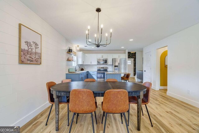 dining room featuring light hardwood / wood-style floors, sink, and an inviting chandelier