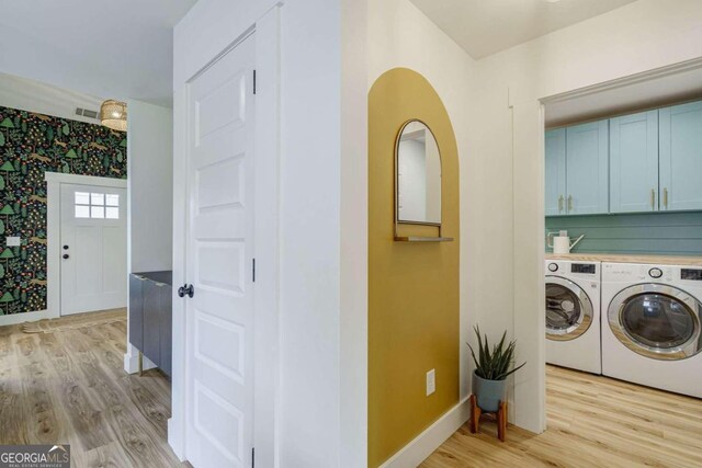 laundry area featuring cabinets, light hardwood / wood-style floors, and separate washer and dryer