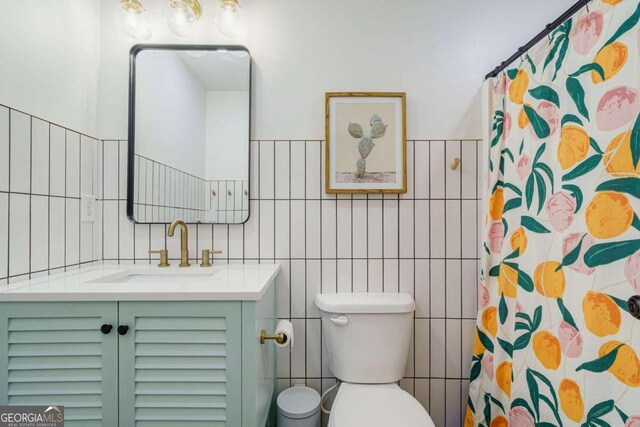 bathroom with tile walls, walk in shower, vanity, and toilet