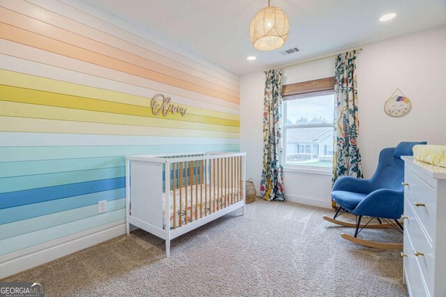 bedroom with carpet, a nursery area, and wood walls