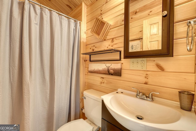 bathroom featuring wood walls, toilet, and vanity