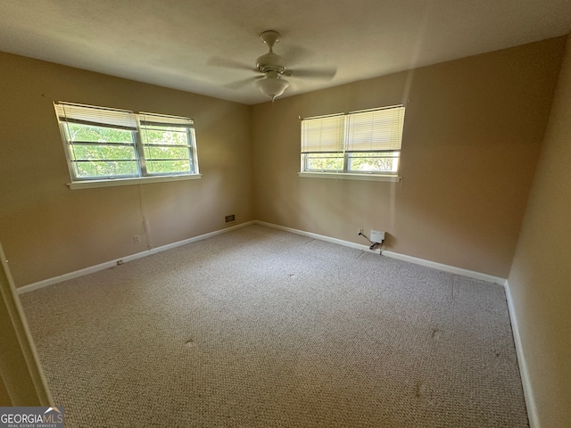 carpeted spare room featuring a wealth of natural light and ceiling fan