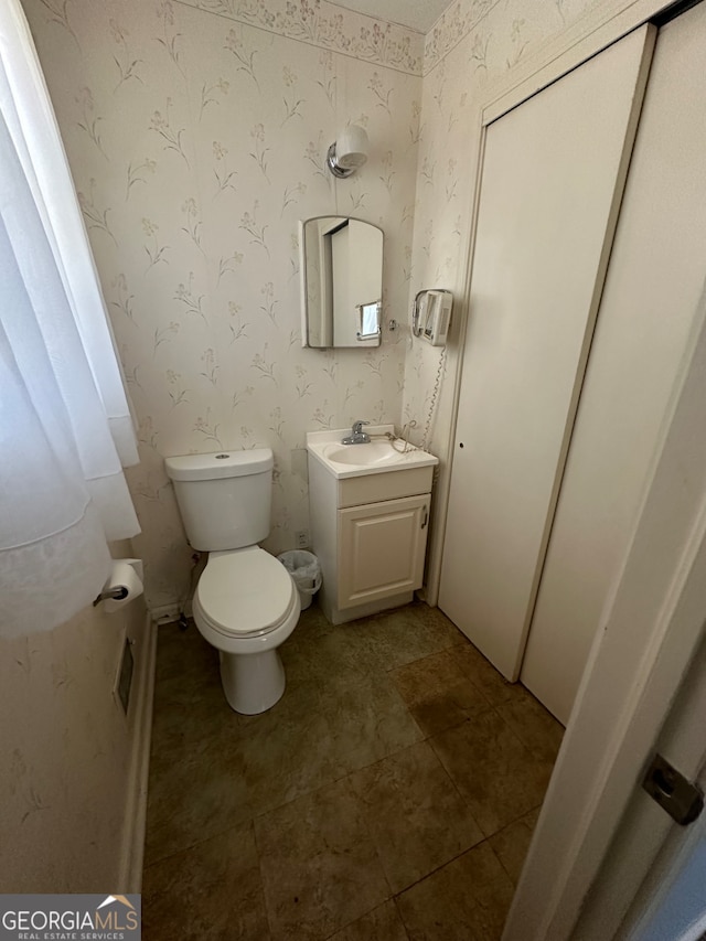 bathroom with toilet, vanity, and tile patterned flooring