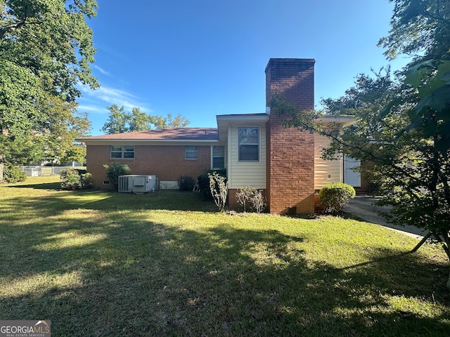 back of property featuring a lawn, cooling unit, and a garage