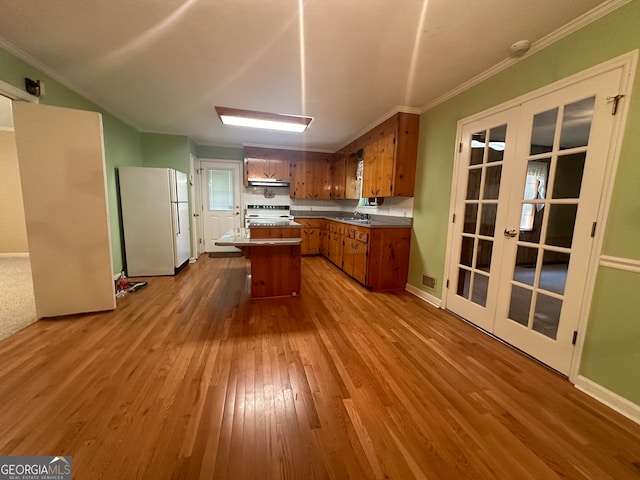 kitchen featuring white appliances, french doors, light hardwood / wood-style floors, and a center island