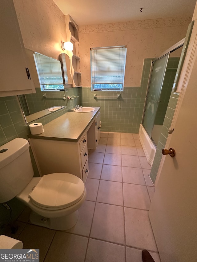 full bathroom featuring toilet, combined bath / shower with glass door, tile walls, and tile patterned floors