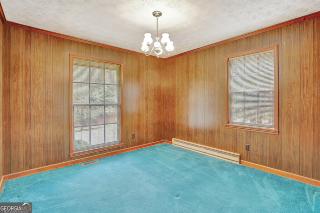 spare room featuring a baseboard heating unit, carpet flooring, a healthy amount of sunlight, and a chandelier