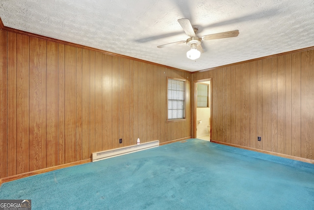 carpeted spare room featuring a textured ceiling, a baseboard radiator, wooden walls, and ceiling fan