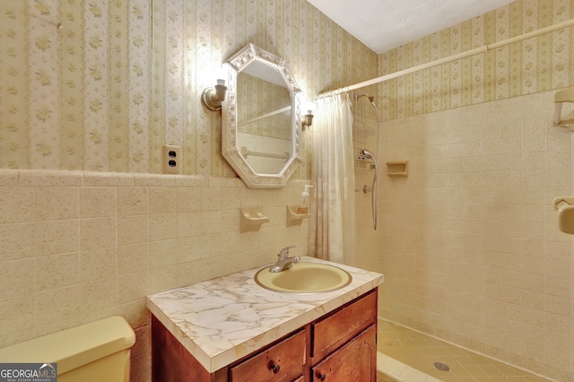 bathroom with curtained shower, vanity, toilet, and tile walls