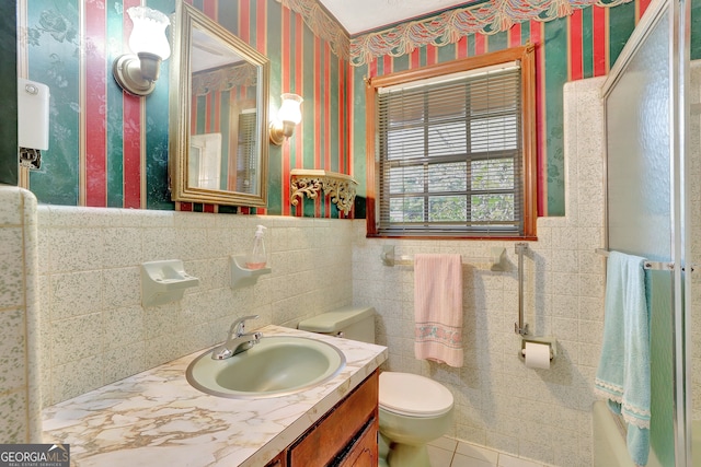 bathroom featuring tile patterned flooring, vanity, toilet, and tile walls