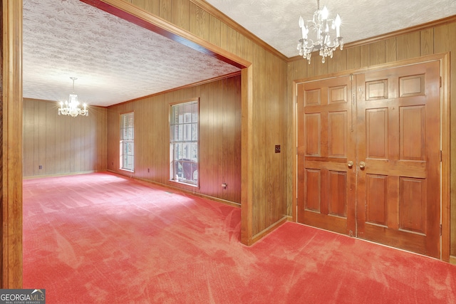 foyer with a chandelier, wooden walls, a textured ceiling, and carpet