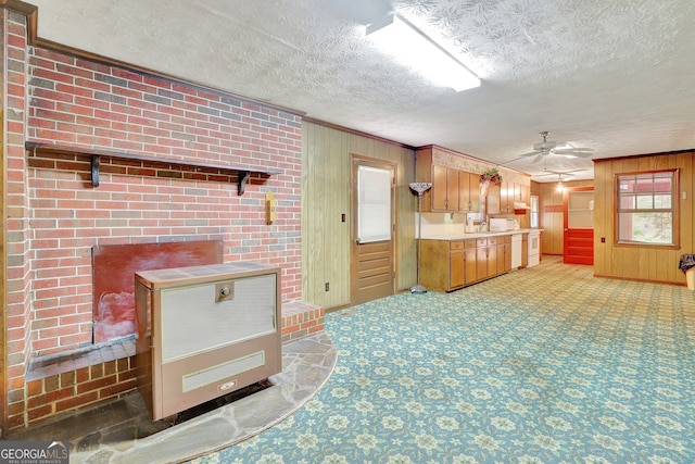 kitchen featuring ornamental molding, a textured ceiling, wooden walls, ceiling fan, and brick wall