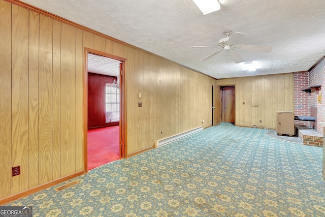 unfurnished living room featuring carpet flooring, a textured ceiling, baseboard heating, ceiling fan, and crown molding