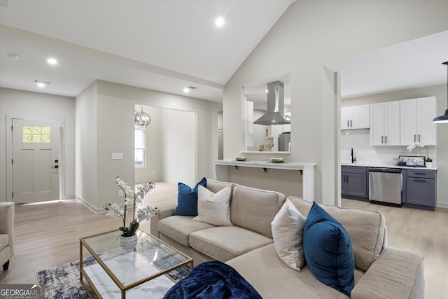 living room featuring high vaulted ceiling, a chandelier, and light wood-type flooring