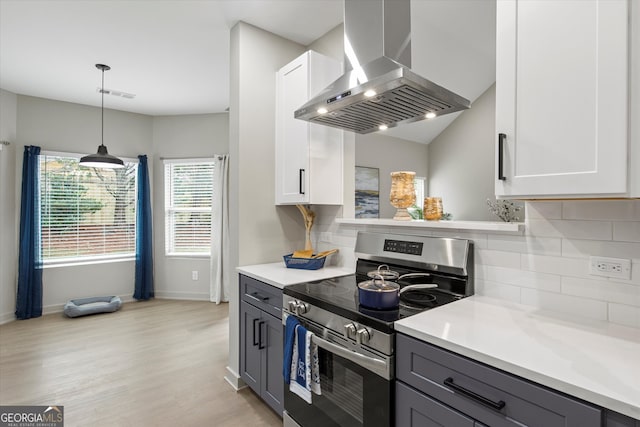 kitchen with gray cabinets, white cabinetry, stainless steel range oven, and wall chimney range hood