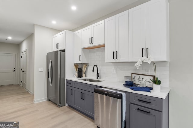 kitchen featuring gray cabinetry, sink, appliances with stainless steel finishes, light hardwood / wood-style floors, and white cabinetry