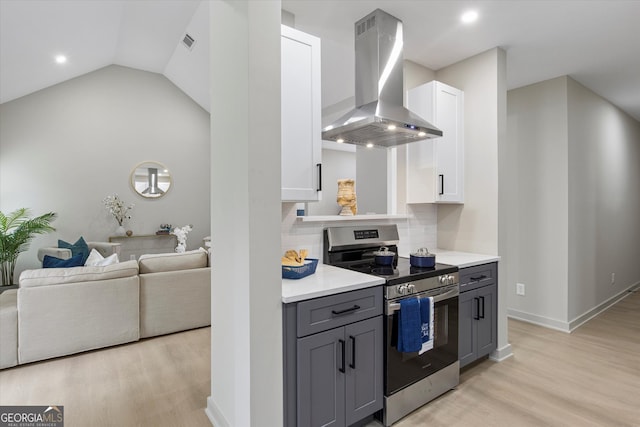 kitchen featuring wall chimney range hood, decorative backsplash, gray cabinets, stainless steel range oven, and white cabinetry