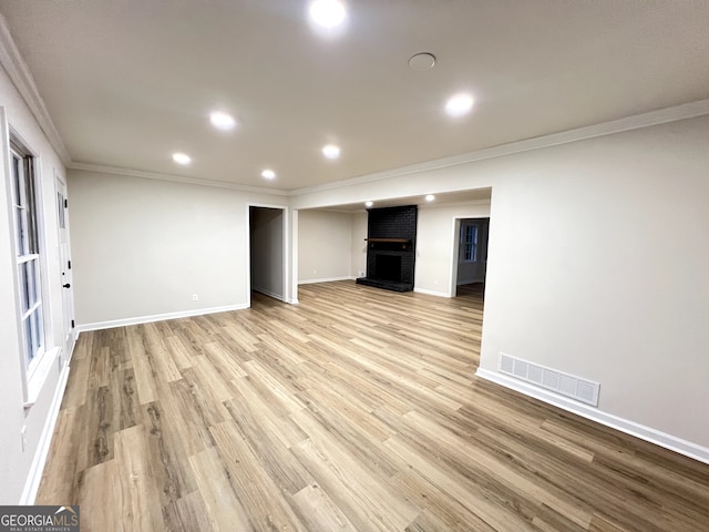 unfurnished living room with a fireplace, light wood-type flooring, and ornamental molding